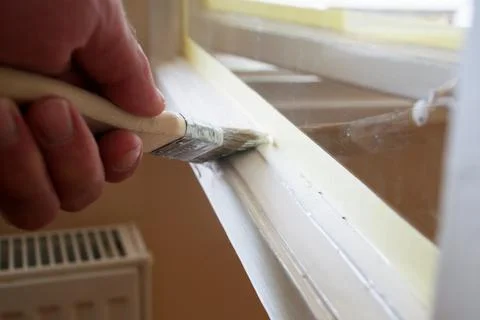Painting a Window Frame with White Paint During Home Renovation Stock Photos