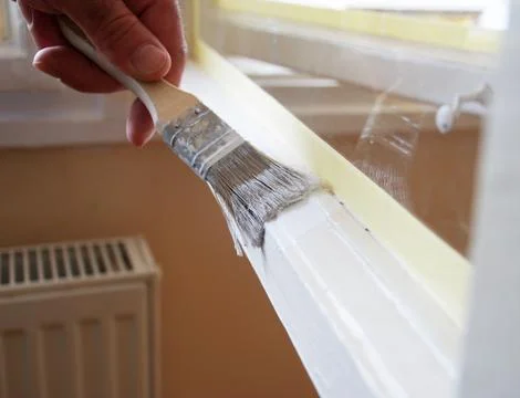 Painting a Window Frame with White Paint During Home Renovation Stock Photos