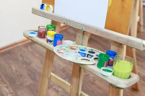 Paints of the artist on an easel in a clase Stock Photos