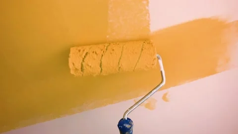 Paints a wall in orange with a roller Stock Footage 141080557