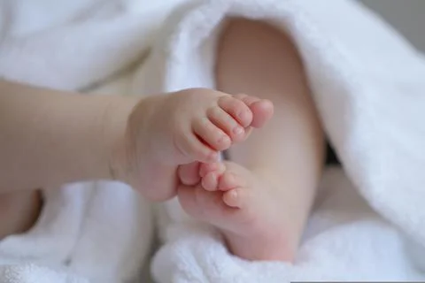 A pair of baby's tiny feet wrapped in a white towel 스톡 사진