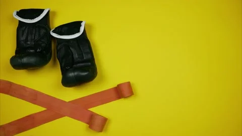 A pair of black boxing gloves and protective tape on yellow background Stock Footage 150085233