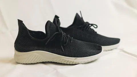 Pair of black mesh sneaker with white sole on light background. Modern sport  Stock Photos