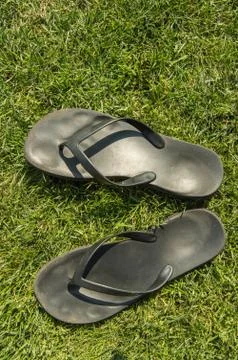 A pair of black rubber flip-flops on the green lawn grass with a copy of the  Stock Photos