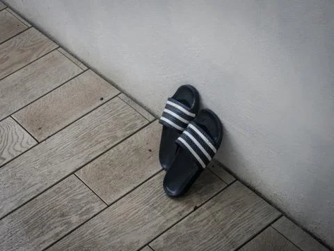 Pair of blue and white plastic sandals leaning against wall outdoors Stock Photos