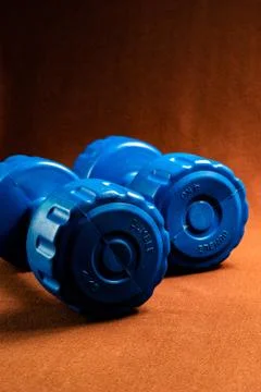 A pair of Blue dumbbells kept on a table Stock Photos