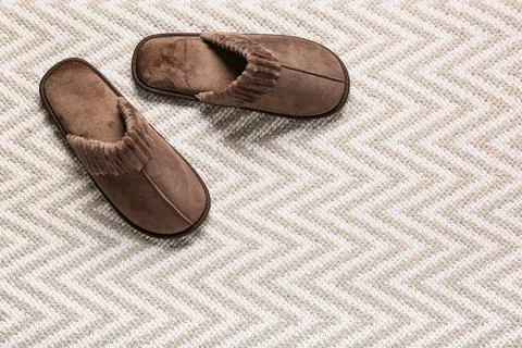 Pair of brown slippers on patterned carpet Stock Photos