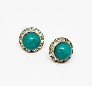 Pair of button earrings with turquoise stone surrounded by rhinestones on whi Stock Photos