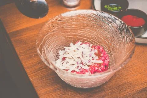 A pair of chef hands preparing Beef tartare with Sbrinz cheese and rucola sal Stock Photos