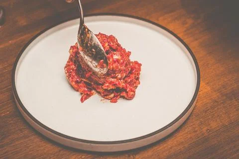 A pair of chef hands preparing Beef tartare with Sbrinz cheese and rucola sal Stock Photos