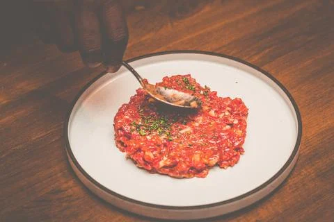 A pair of chef hands preparing Beef tartare with Sbrinz cheese and rucola sal Stock Photos