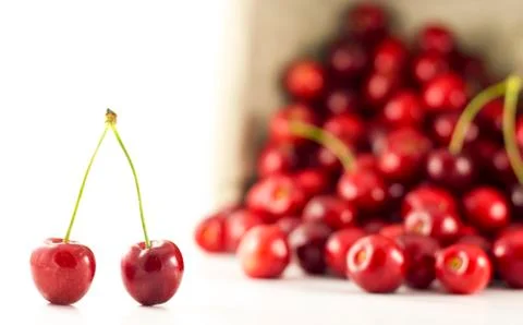 A pair of cherries with spilled cherries in the background Stock Photos