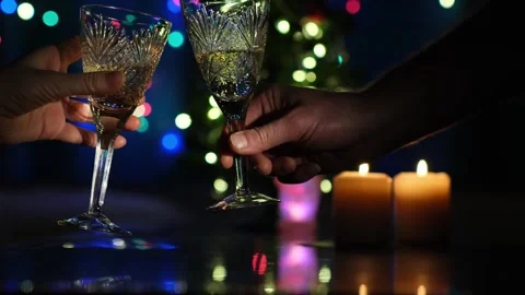 Pair of clinking glasses filled with champagne on blinking garlands background. Stock Footage 256392053