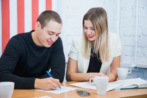Pair of creative young people sit and work together sign document 库存照片