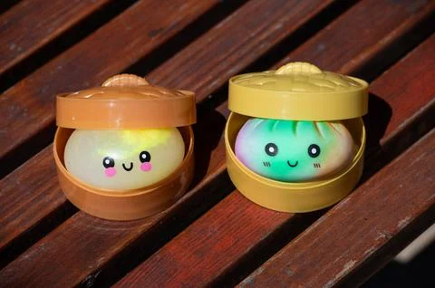 Pair of cute dumpling squishy toys on wooden surface outdoors Stock Photos