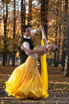 Pair of dancers dancing in the woods. Man with suit, woman in yellow long dre Stock-Fotos