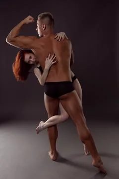 A pair of dancers in an elegant acrobatic pose against a dark background. Stock Photos