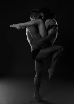 A pair of dancers in an elegant acrobatic pose against a dark background. Stock Photos