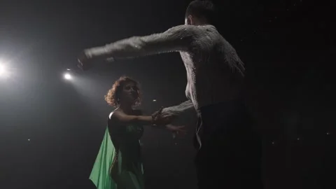 Pair of dancers in light of spotlights perform hand movements adopted in latino Stock Footage 275341178