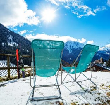 Pair of deck chairs and ski over mountains view Fotos Stock
