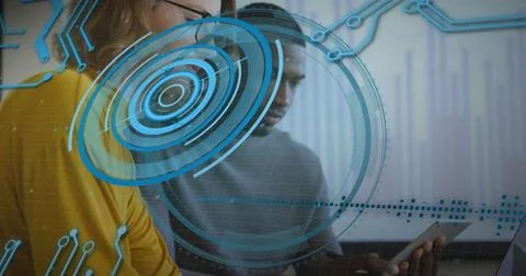Pair at desk typing and tapping screens, initiating blue tech HUD centering data Stock Photos