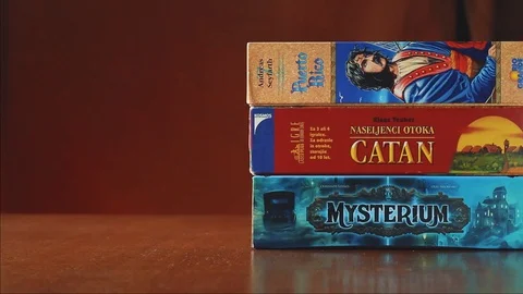 Pair of dice rolling in front of stack of board games on the table Video stock 123542997