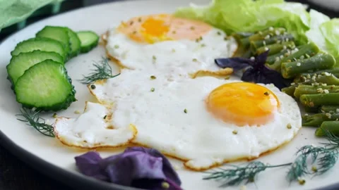 A pair of eggs fried in organic vegetable oil and served on a white serving Video stock 220082546