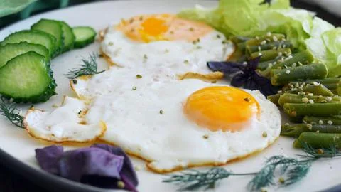 A pair of eggs fried in organic vegetable oil and served on a white serving Stock Photos