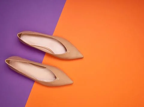 A pair of elegant light brown pointed-toe ballet flats on a two-colored bac.. Stock Photos