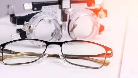 A pair of eyeglasses sits on a table next to a device that measures the dis.. Stock Photos