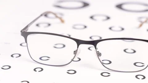A pair of eyeglasses is on a table with a circle patterned background Stock Photos