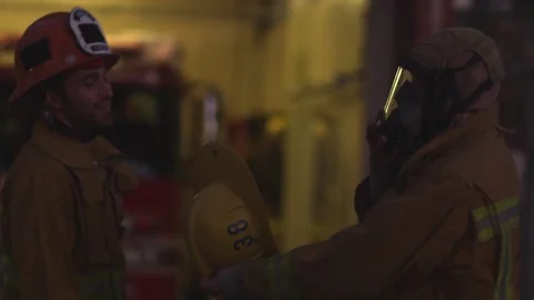 A pair of firefighters remove their gear outside the firehouse. Stock Footage 69175396