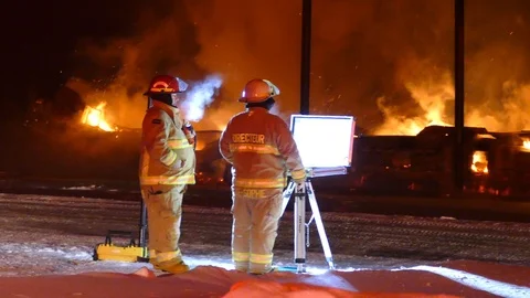 Pair of firemen standing at command post with flames burning in background Video stock 123204818