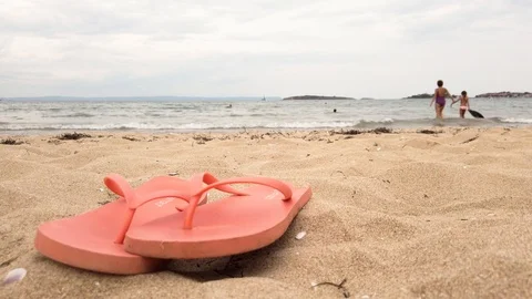 A pair of flip flops on a sandy beach. Mother and daughter holding hands. Stock Footage 114303000