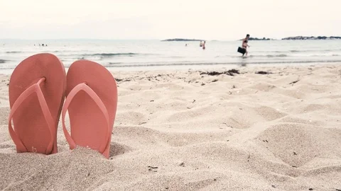 A pair of flip flops sticking out on a sandy beach. Cloudy beach landscape. Stock Footage 114317823