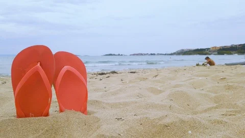 A pair of flip flops sticking out on a sandy beach. Stock Footage 114438705