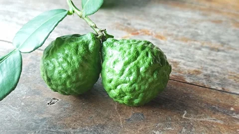A pair of fresh green kaffir lime fruits on wooden table. Vídeo Stock 339203781