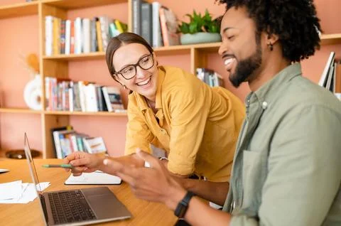 Pair of friendly colleagues work in office. Young businessman explains to his Stock Photos