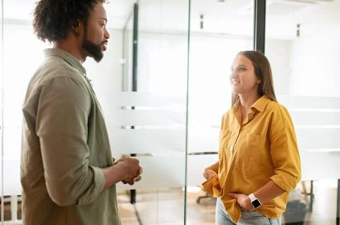 Pair of friendly colleagues work in office. Young business people are talking in Stock Photos