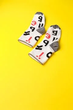 Pair of funny white socks with different Ukrainian letters on bright yellow Stock Photos