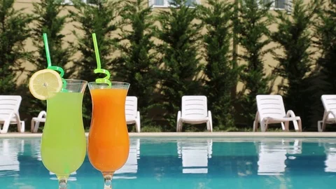 A pair of glasses with a cocktail on the poolside Stock Footage 84650293