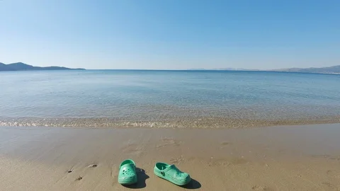 A pair of green rubber sandals on a sandy beach Video stock 130120258
