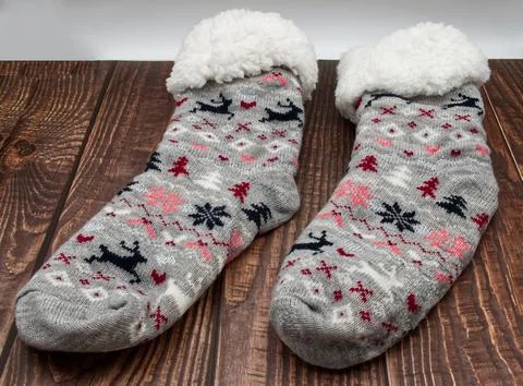 A pair of grey knitted winter socks with reindeer patterns. 库存照片