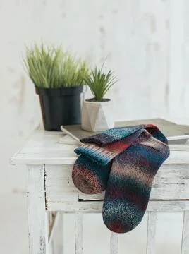 Pair of hand knitted socks on the table. Multi-colored socks. Stock Photos
