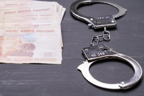 A pair of handcuffs is on a table next to a pile of money Stock-Fotos