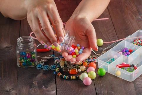 Pair of hands and pliers assembling a bead necklace. Stock Photos
