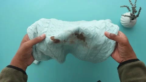 Pair of hands holding dirty light blue sweater with stains in close-up dyna.. Vídeos de archivo 332545537