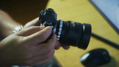 A pair of hands holds a camera with an attached lens and controls it. Stock-Footage 335852701