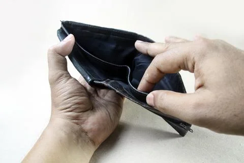 A pair of hands holds an open, empty black leather wallet. The wallet's int.. Фото