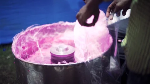 A Pair of hands making cotton candy in a spinning pink fluffy maker in Stock Footage 97361870